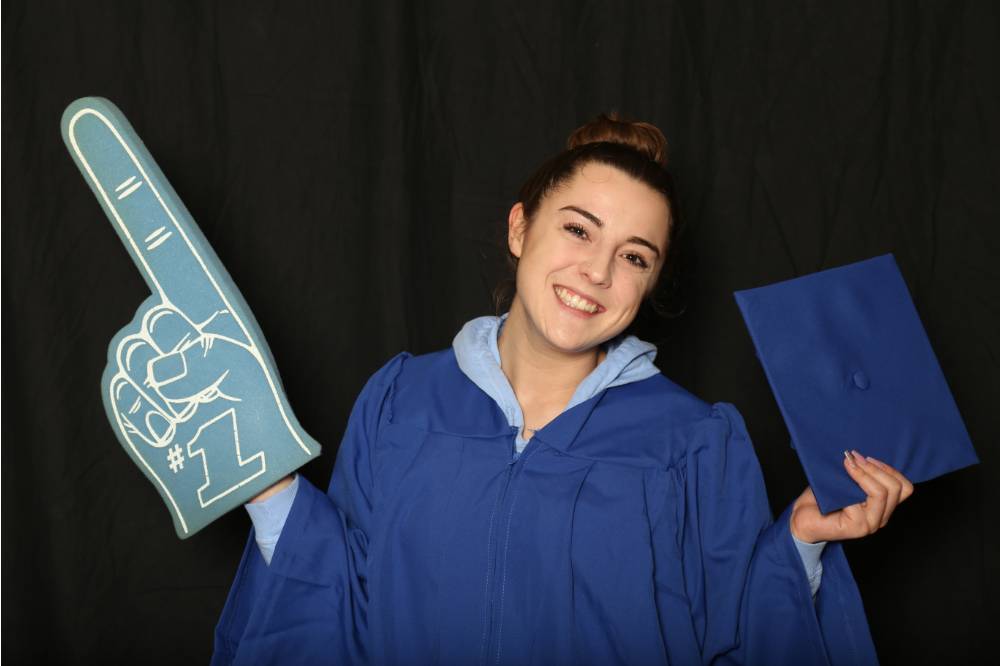 student posing with graduation cap and foam finger